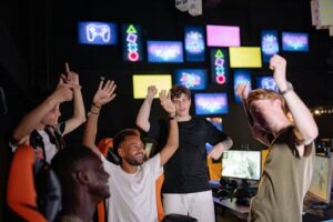 A diverse group of young men celebrating victory in a vibrant gaming room.