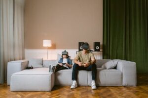 A man and child enjoying video games with VR headsets on a modern couch at home.