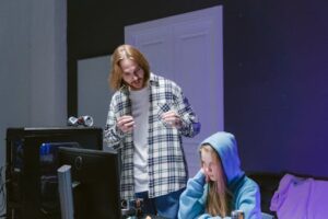 A young man and woman engrossed in a computer game setup indoors with a modern gaming environment.