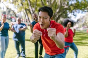 Diverse group enjoying a spirited team building game in a sunny park setting.