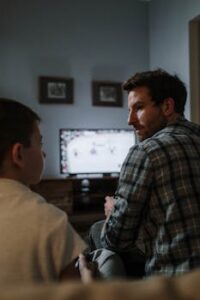 Father and son enjoying a gaming session on the weekend in a cozy living room setting.