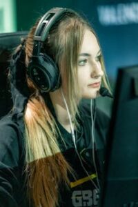 Professional female gamer wearing headphones, focused on gaming during an esports tournament.