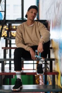 Young man in casual outfit sitting on colorful stairs with a video game controller.